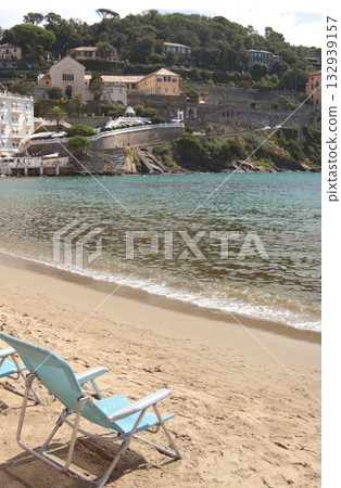 Deck chair on seashore in bay. Relaxing on sandy beach in Italy. Vacation and travel. Deck chair on seashore in bay. Relaxing on sandy beach in Italy. Vacation and travel. 132939157
