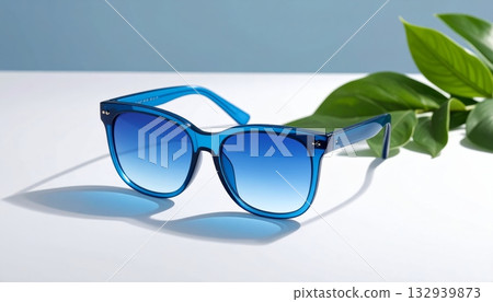 Black plastic fashion sunglasses with a blue lens reflection against a white isolated background and blue sky on the summer beach 132939873