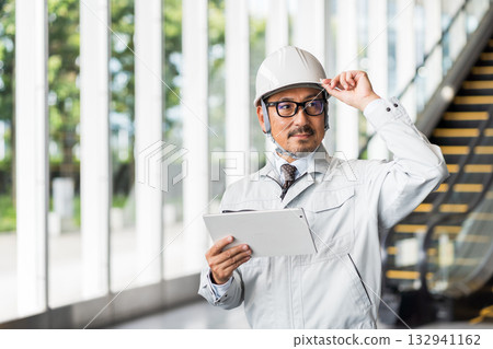 一位中年男性工地主管正在看平板電腦。 132941162