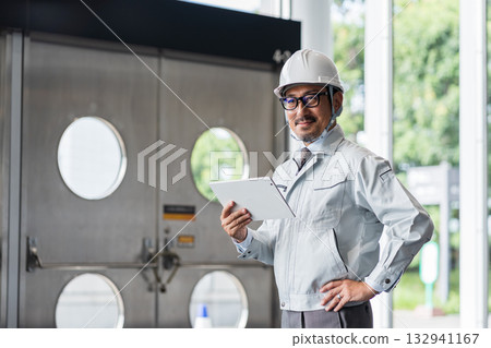 A middle-aged male site supervisor looking at a tablet. A middle-aged male site supervisor looking at a tablet. 132941167