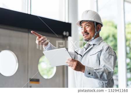 A middle-aged male site supervisor looking at a tablet. 132941168