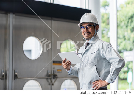 一位中年男性工地主管正在看平板電腦。 132941169