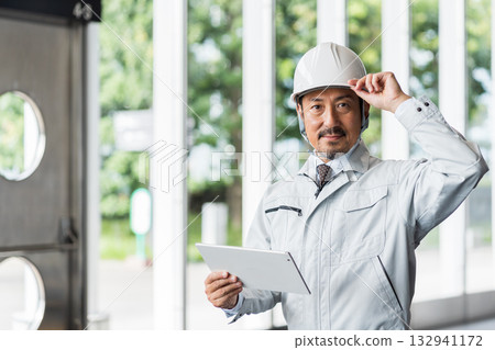 一位中年男性工地主管正在看平板電腦。 132941172