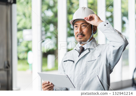 一位中年男性工地主管正在使用平板電腦查看資訊。 132941214