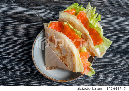 Homemade salmon flatbread on a table in a cafe. Homemade salmon flatbread on a table in a cafe. 132941242