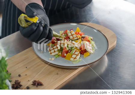 The chef seasons the salad with sauce. The chef seasons the salad with sauce. 132941306