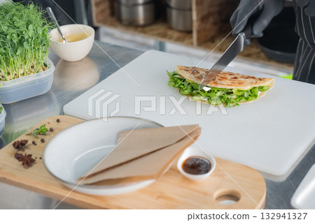 The chef prepares a flatbread with herbs. The chef prepares a flatbread with herbs. 132941327