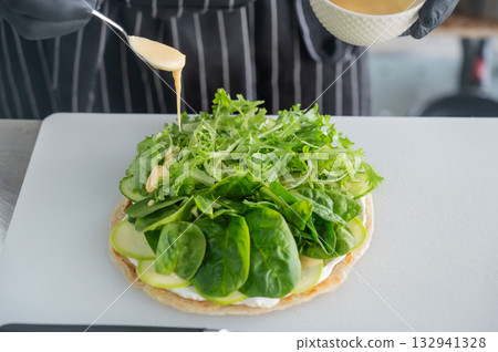 The chef prepares a flatbread with herbs.  132941328
