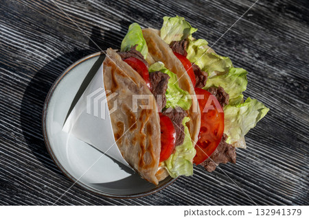 Homemade flatbread with beef and tomatoes on a table in a cafe.  132941379