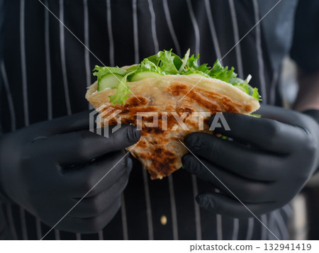 Chef holding a flatbread with herbs. Chef holding a flatbread with herbs. 132941419