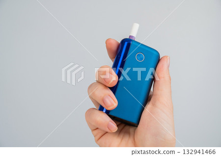 Woman holding electronic cigarette on white background. Tobacco heating systems. Woman holding electronic cigarette on white background. Tobacco heating systems. 132941466