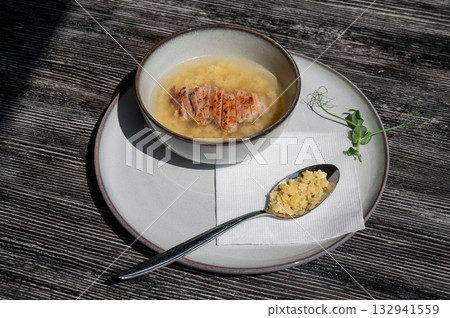 Chicken broth with noodles on a wooden table.  132941559