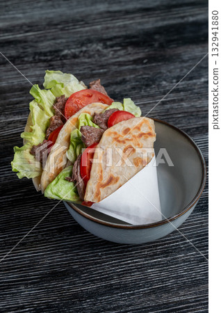Homemade flatbread with beef and tomatoes on a table in a cafe.  132941880