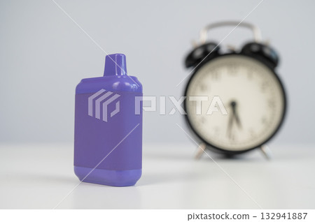Disposable vape and alarm clock on white background.  132941887
