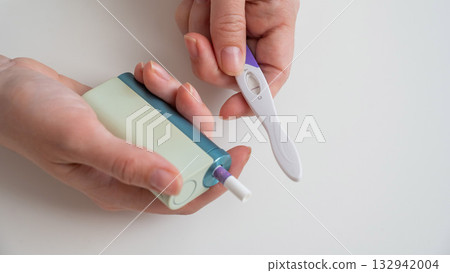 Woman holding pregnancy test and e-cigarette.  132942004