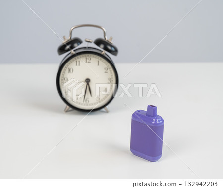 Disposable vape and alarm clock on white background. Disposable vape and alarm clock on white background. 132942203