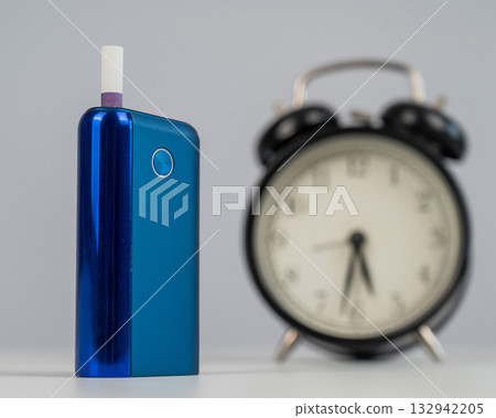 Electronic cigarette and alarm clock on white background. Tobacco heating systems. 132942205