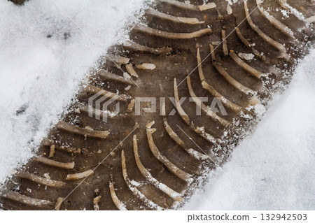 Tire tracks left in fresh snow show signs of recent activity on a rural road during winter 132942503