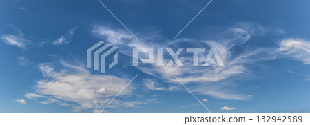 Vast blue sky with wispy clouds scattered across a sunny day showcasing the beauty of nature and tranquility above 132942589