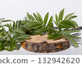 A white background with a wooden podium and green leaves to showcase your product and advertise. 132942620