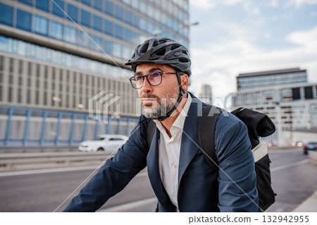 City commuter riding bike to office, wearing backpack and helmet. 132942955