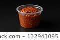 Spicy Chili Sauce in Plastic Container on Black Background, Close-Up Shot 132943095