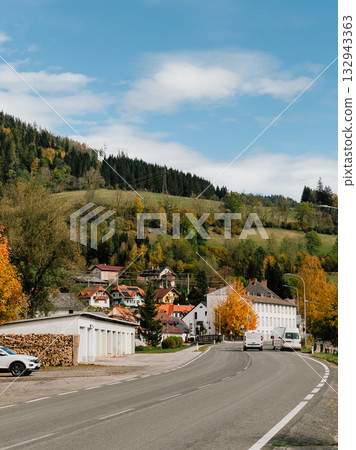 Two delivery vans driving along winding road toward small village nestled in Black Forest mountains of Germany on sunny autumn day with vibrant foliage. Delivery vans navigating curving mountain road Two delivery vans driving along winding road toward small village nestled in Black Forest mountains of Germany on sunny autumn day with vibrant foliage. Delivery vans navigating curving mountain road 132943363