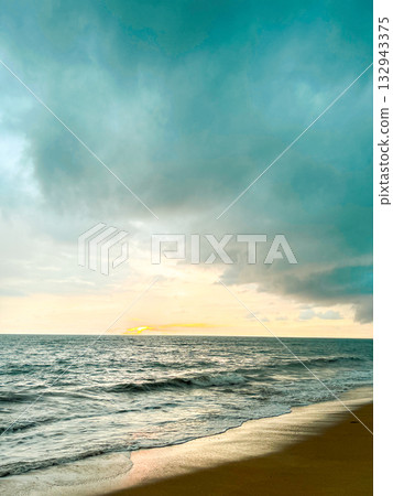 Dramatic moody sunset over ocean with soft waves and golden sand beach 132943375
