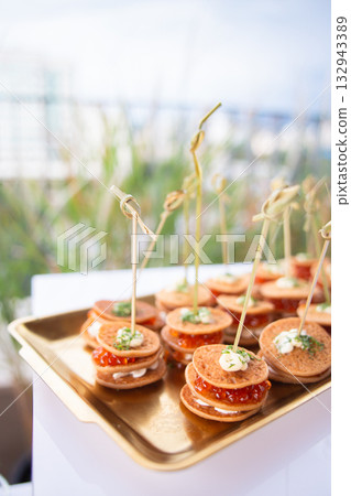 Mini pancake canapes with cream cheese and red caviar on golden tray 132943389