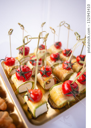 Elegant zucchini rolls with cheese and cherry tomatoes on golden serving tray Elegant zucchini rolls with cheese and cherry tomatoes on golden serving tray 132943410
