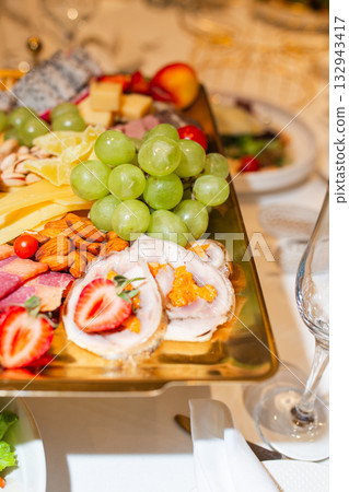 Luxury charcuterie board with grapes, cheese, nuts and fruit on golden tray 132943417