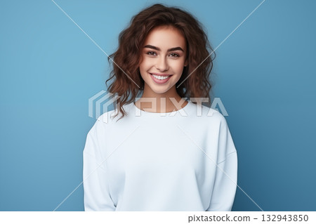 Portrait of a beautiful young woman smiling and looking at camera isolated on a blue background 132943850