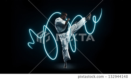 Karate fighter performing high kick with glowing neon motion effect Karate fighter performing high kick with glowing neon motion effect 132944148