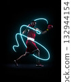 Professional boxer in red gloves throwing punch with bright neon energy trail in dark studio 132944154