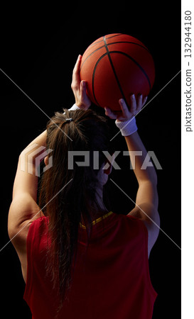 Female athlete raising basketball overhead preparing to shoot with focus 132944180