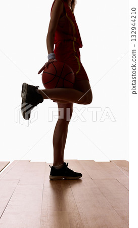 Female basketball player standing holding ball and stretching leg before game 132944210