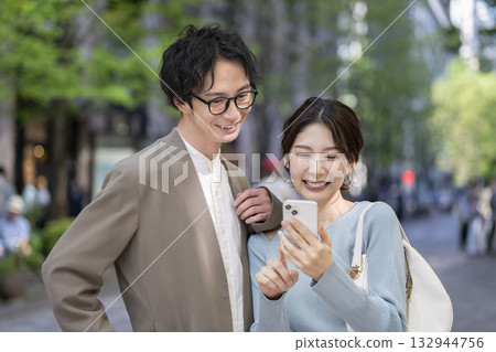 微笑的三十多歲男女正在看著智慧型手機 132944756