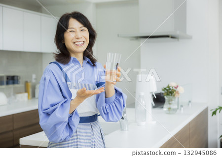 Woman drinking water in the kitchen 132945086