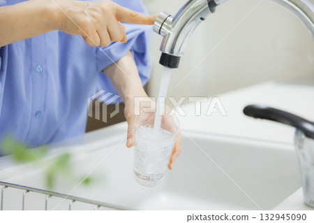 Woman drinking water in the kitchen Woman drinking water in the kitchen 132945090