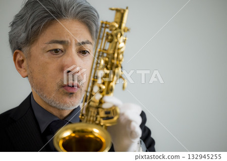 Senior man performing maintenance on a saxophone 132945255
