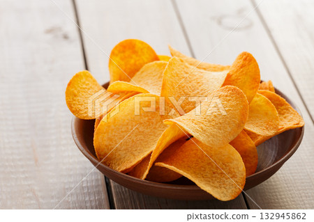 Golden Crispy Potato Chips in Bowl on Wooden Table 132945862