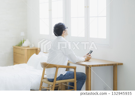 Man looking at smartphone in bedroom Man looking at smartphone in bedroom 132945935