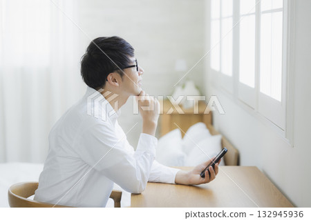 Man looking at smartphone in bedroom 132945936