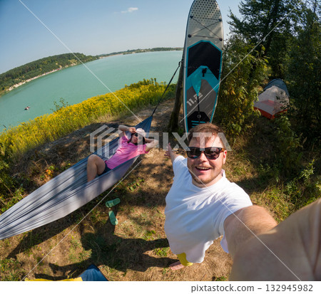 Couple Enjoying Lakeside Camping with Paddleboard 132945982