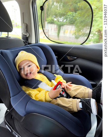 Smiling Baby in Car Seat with Yellow Sweater and Hat 132946037