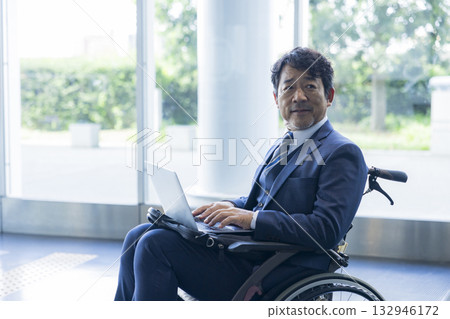 一名身穿西裝的男子坐在輪椅上 132946172