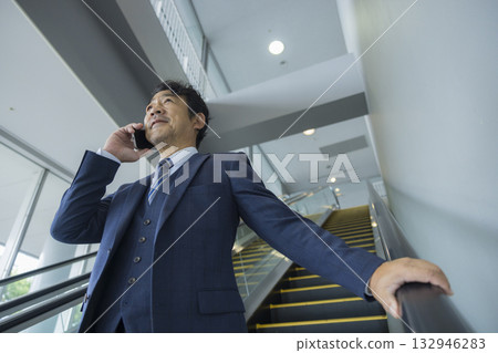 Businessman riding escalator 132946283