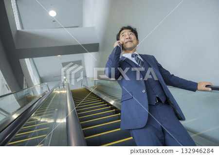 Businessman riding escalator Businessman riding escalator 132946284
