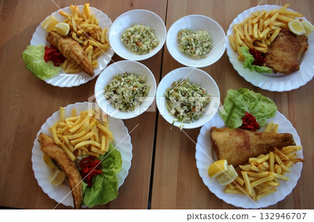 Polish seaside meal with fried fish, fries, and cabbage salad on a wooden table 132946707