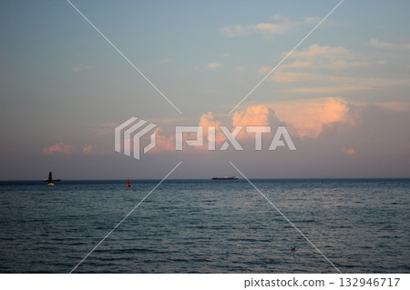 Calm sea horizon with ships and pink clouds at sunset Calm sea horizon with ships and pink clouds at sunset 132946717